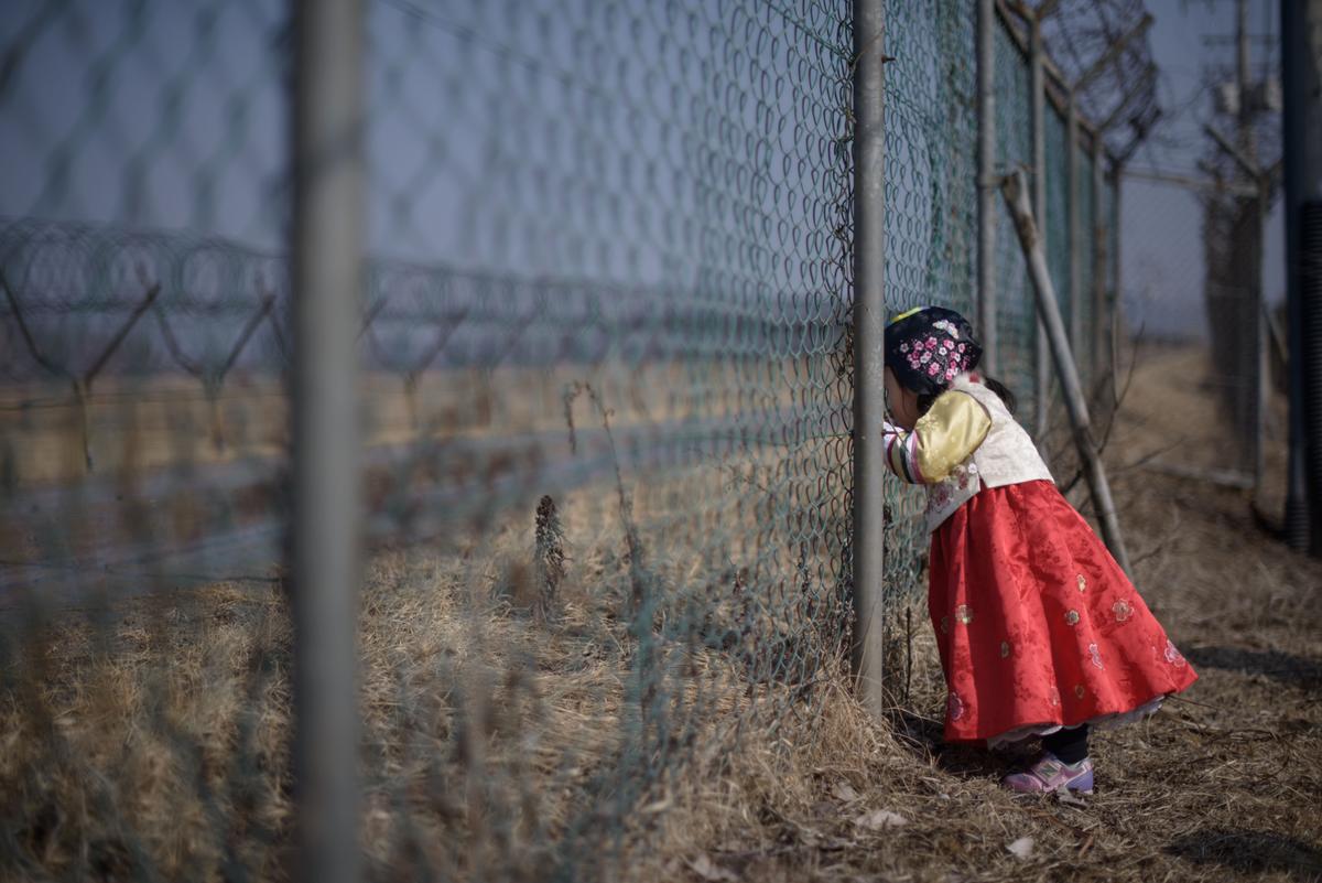 A girl wearing a traditional hanbok dress stands at a military fence facing towards North Korea at Imjingak Park, south of the Military Demarcation Line and Demilitarized Zone (DMZ) separating North and South Korea, on Feb. 19, 2015. (Ed Jones/AFP/Getty Images)