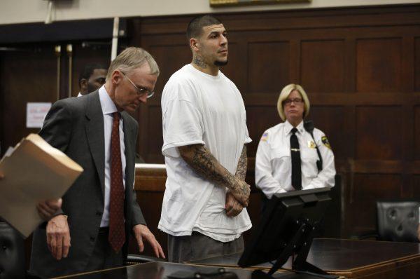 Former New England Patriots NFL football player Aaron Hernandez, center, stands with defense attorney Charles Rankin, left, at the conclusion of a pre-trial hearing at Suffolk Superior Court in Boston, on Dec. 22, 2015. (Steven Senne/AP)