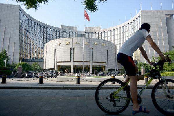 A man rides his bike in front of the People’s Bank of China in Beijing on Aug. 12, 2015. (Wang Zhao/AFP/Getty Images)