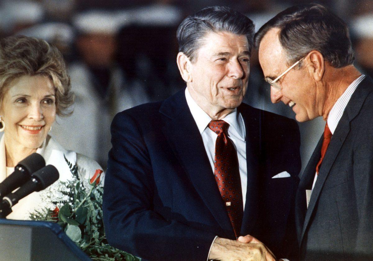 President Ronald Reagan (C) shakes hands with Vice President George Bush (R) as First Lady Nancy Reagan (R) looks on at Andrews Air Force Base, in Md., on June 3, 1988. (Luke Frazza/AFP/Getty Images)
