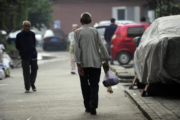 An elderly man (C) makes his way home after buying some vegetables from a market in Beijing on Sept. 7, 2012. Seniors will be the first to have their pensions cut as China edges closer to a financial cliff, says He Qinglian. (Wang Zhao/AFP/Getty Images)