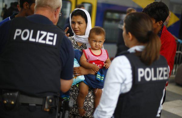German federal police officers talk to a Afghan family after they arrived the main station in Rosenheim, southern Germany, on July 28, 2015. (Matthias Schrader/AP Photo)