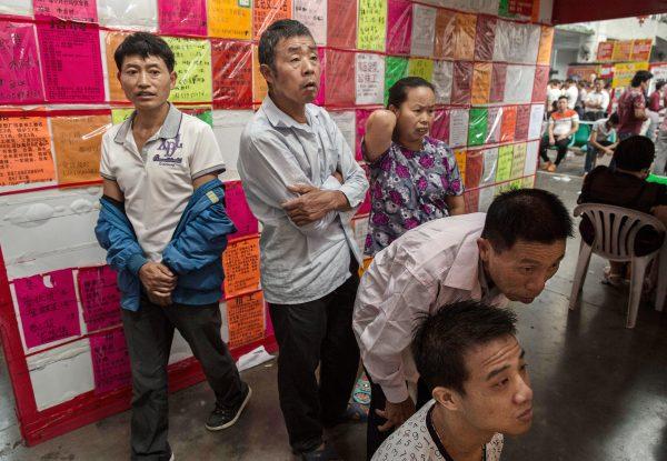 Chinese workers look at bulletin boards showing potential jobs at a local employment center in Yiwu, eastern China's Zhejiang Province on Sept. 18, 2015. (Kevin Frayer/Getty Images)