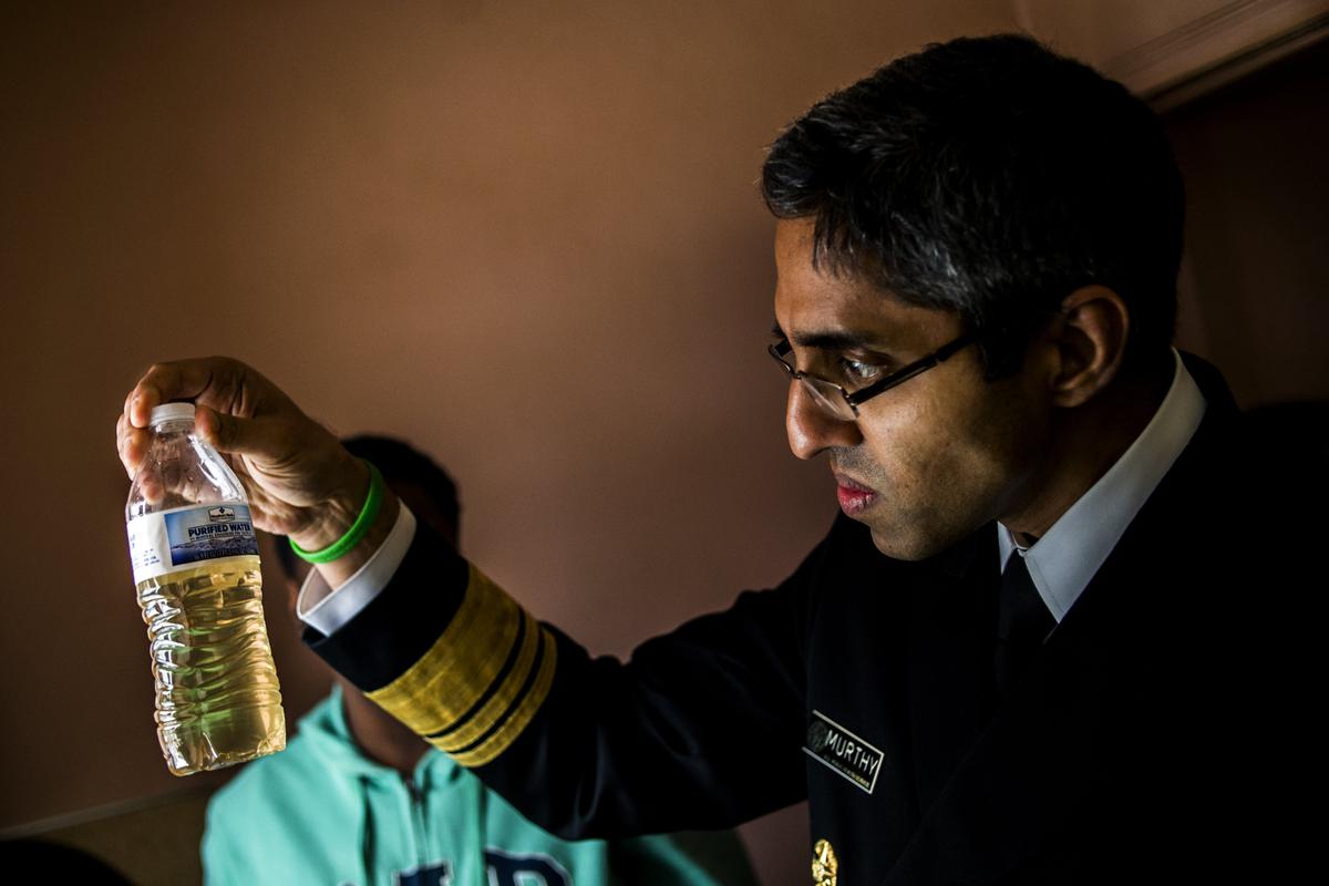 U.S. Surgeon General Vivek Murthy inspects a bottle of water that contains water from Flint resident Tia Simpson's tap at her home on Flint's south side, in Mich., on Feb. 16, 2015. (Jake May/The Flint Journal-MLive.com via AP)