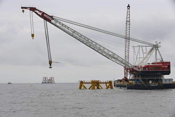 The first foundations are installed by Deepwater Wind in the nation's first offshore wind farm construction project are next to a floating construction crane on the waters of the Atlantic Ocean off Block Island, R.I., on July 27, 2015. (Stephan Savoia/AP Photo)