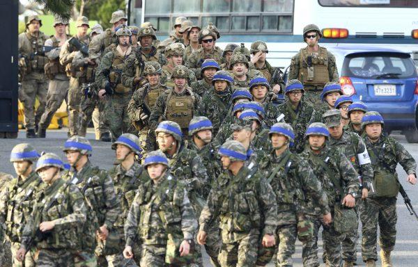 South Korean Marines, wearing blue headbands on their helmets, and U.S. Marines move together during the annual joint military exercise Key Resolve and Foal Eagle by South Korea and the United States in Pohang, South Korea, Monday, March 7, 2016. (Kim Jun-bum/Yonhap via AP)