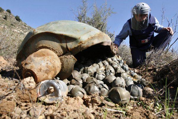 Mines Advisory Group (MAG) Technical Field Manager Nick Guest inspects a Cluster Bomb Unit that was dropped by Israeli warplanes during the 34-day-long Hezbollah-Israeli war, in the southern village of Ouazaiyeh, Lebanon, on Nov. 9, 2006. (Mohammed Zaatari/Associated Press)