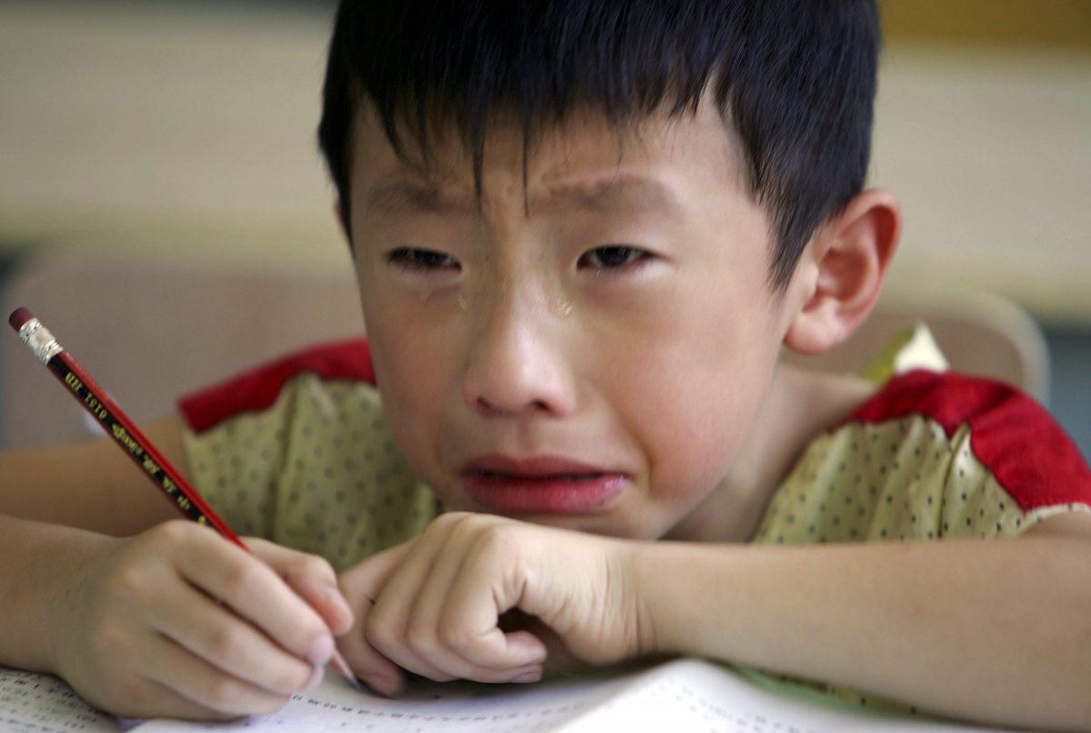 A boy cries during class because he misses his mother at the West Point Training Center in Hangzhou, Zhejiang Province, China, on Aug. 2, 2006. (Cancan Chu/Getty Images)
