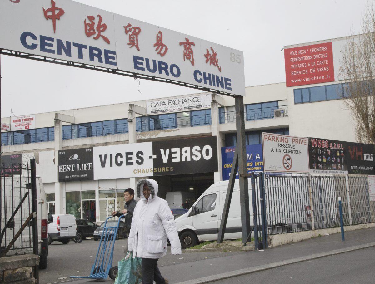 People walk in a Chinese wholesale clothing district in Aubervilliers, north of Paris on Feb. 24, 2016. Chinese merchants are accused of laundering money for North African drug dealers. The sign in Chinese reads "China Europe Trade and Commerce City." (AP Photo/Jacques Brinon)