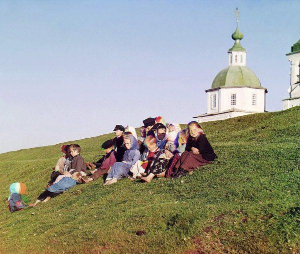 Children sit on the side of a hill near a church and bell tower in the countryside near White Lake, in the north of European Russia in 1909. (File photo)