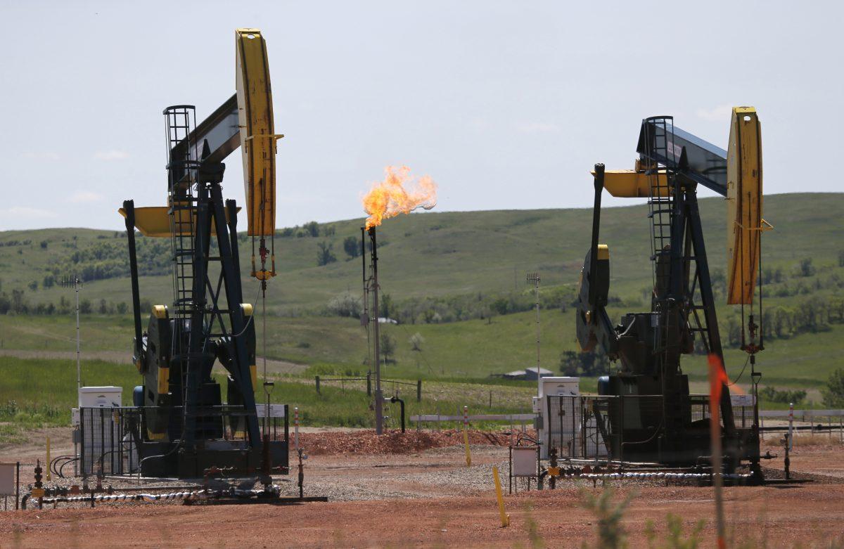 Oil is pumped and natural gas is flared off on an oilfield near Watford City, N.D., on June 12, 2014. (Charles Rex Arbogast/AP)