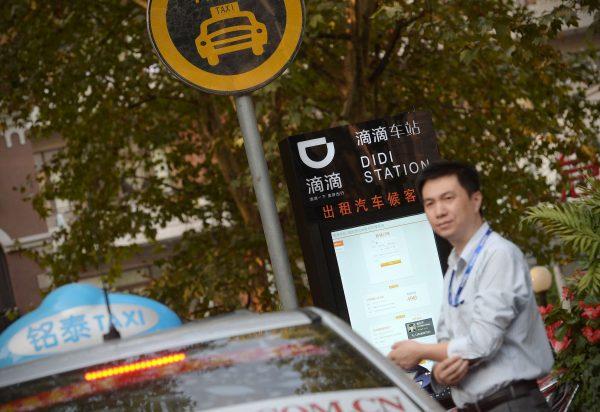 In this file photo, a taxi driver waits at a Didi Station, a roadside stop for taxis booked by the Chinese car-hailing app Didi Chuxing in Shanghai, China. (Chinatopix via AP)