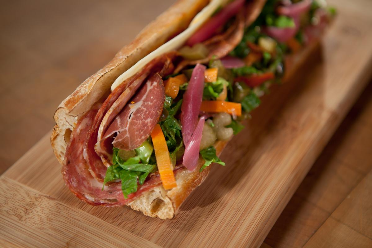Make a stop at Goose the Market to stock up on local artisanal products and fantastic sandwiches like the Batali (above), a moreish combination of spicy salami meats, bright pickled onions, and provolone. (Courtesy of Goose the Market)