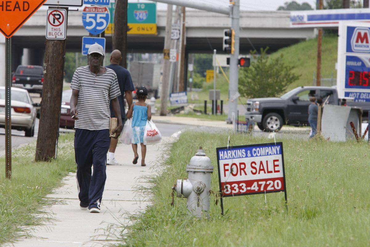 Pedestrians walk past a "for sale" sign on Elvis Presley Boulevard in Memphis, Tenn., on May 31, 2016. The U.S. economy has added a healthy average of roughly 200,000 jobs a month since 2011. (AP Photo/Karen Pulfer Focht)