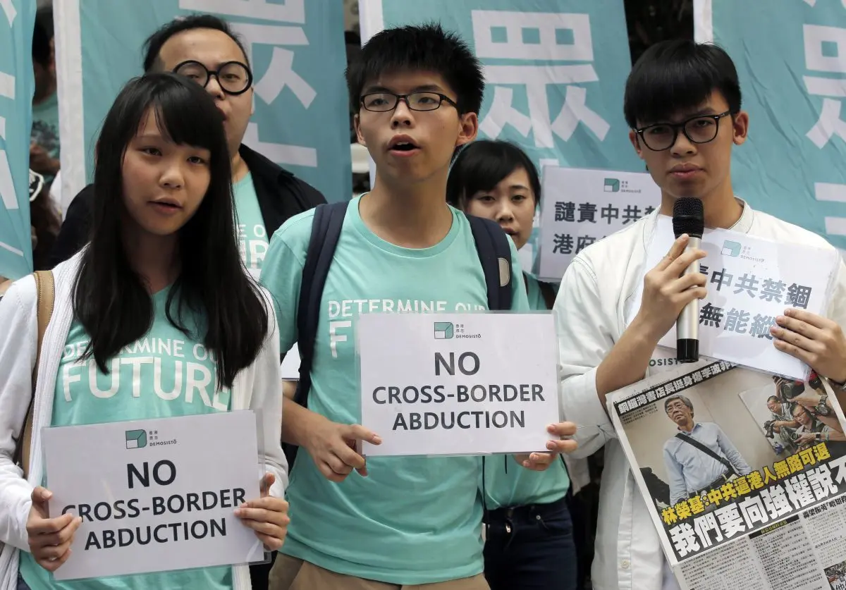 Members of pro-democracy group Demosisto hold placards and a newspaper with a picture of Hong Kong bookseller Lam Wing-Kee during a protest in Hong Kong on June 17, 2016, as they march to the Chinese central government's liaison office. (Kin Cheung/AP Photo)