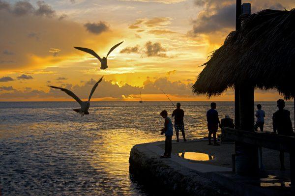 Young teens fish off a Fiesta Key, Fla., at sunset while seagulls hover waiting for fish scraps tossed into the bay on June 25, 2016. (Andy Newman/Florida Keys News Bureau via AP)