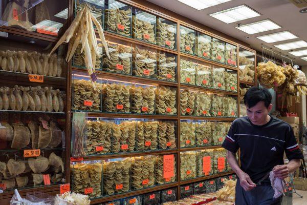 An employee walking past cabinets containing different varieties of dried fish maws and shark fins (top L) in Hong Kong on March 29, 2016. (Anthony Wallace/AFP/Getty Images)
