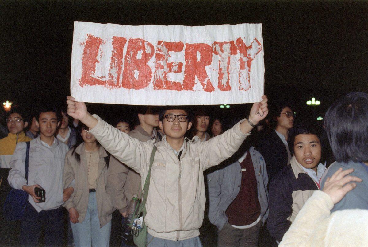 Student displays a banner with one of the slogans chanted by the crowd of some 200,000 pouring into Tiananmen Square in Beijing, on April 22, 1989, in an attempt to participate in the funeral ceremony of former Chinese Communist Party leader and liberal reformer Hu Yaobang during an unauthorized demonstration to mourn his death.  (Catherine Henriette/AFP via Getty Images)