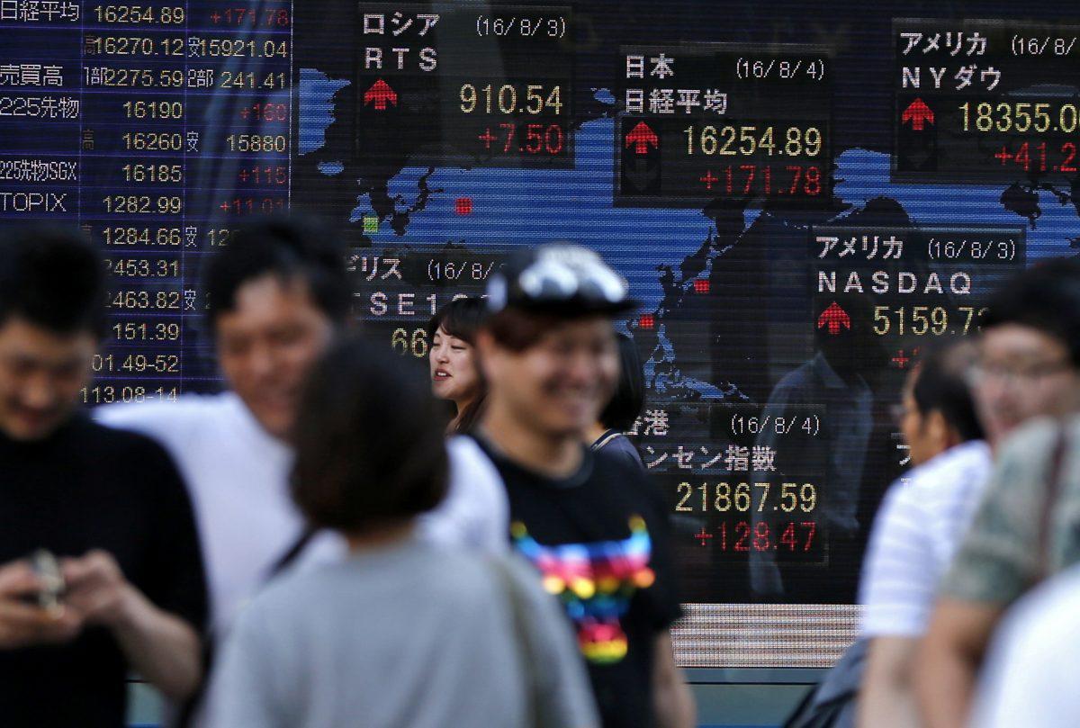 People walk past the electronic board showing the Nikkei stock index in Tokyo on June 16, 2016. (AP Photo/Shuji Kajiyama)