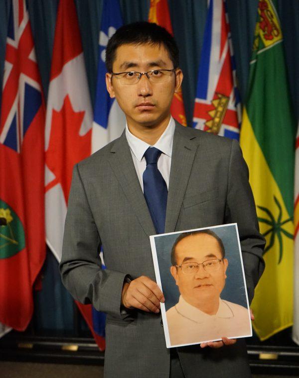 Falun Gong practitioner Paul Li holds a photo of his father <span style="font-weight: 400;">Li Xiaobo,</span> arrested in China and sentenced to eight years in prison. (Pam McLennan/The Epoch Times)