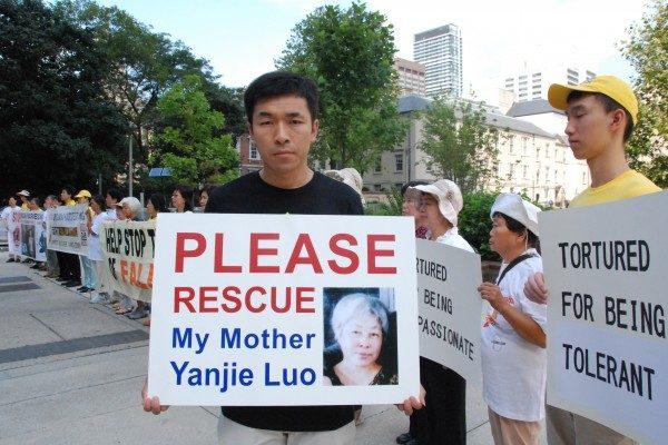 Wenta Fan holds a sign with a portrait of his mother, Yanjie Luo, who in 2011 was sentenced to 13 years in prison in China for practising Falun Gong, outside Toronto City Hall on Aug. 25, 2016.  (Yi Ling/Epoch Times)