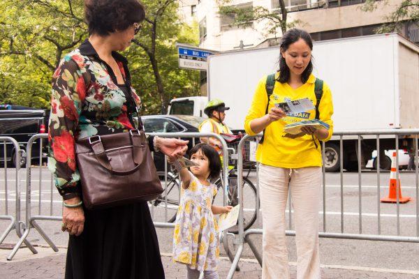 A little girl and her mother hand out pamphlets about the Falun Gong practice in New York on Sept. 20, 2016. (Larry Dai/Epoch Times)