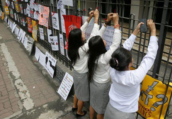 Students from St. Paul's University, a Roman Catholic university, tie red ribbons as they come out from their campus to protest the killings being perpetrated in the unrelenting "War on Drugs" campaign of President Rodrigo Duterte in Manila, Philippines, on Sept. 30, 2016. (AP Photo/Bullit Marquez)