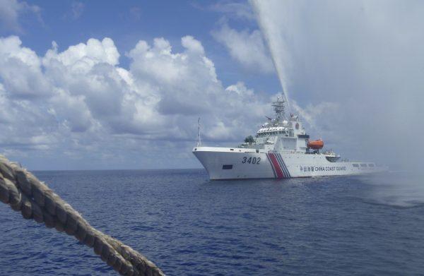 Chinese Coast Guard members approach Filipino fishermen as they confront each other off Scarborough Shoal in the South China Sea, also called the West Philippine Sea, on Sept. 23, 2015. (AP Photo/Renato Etac)
