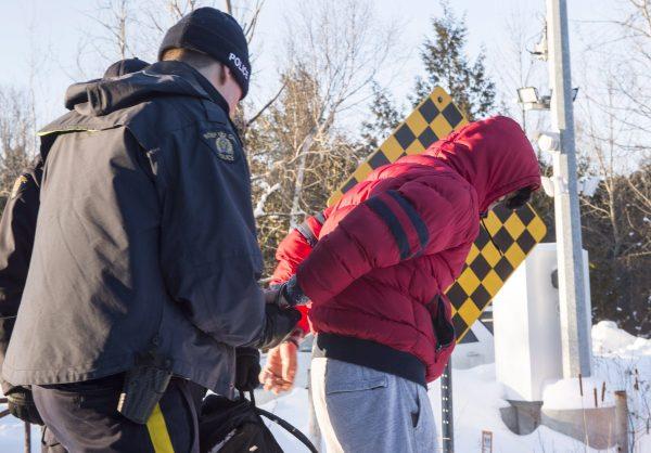 A young man from Yemen is handcuffed by an RCMP officer after crossing the border into Canada near Hemmingford, Que., on Feb. 17, 2017. (The Canadian Press/Paul Chiasson)