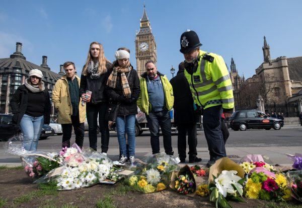 A police officer along with other bystanders at a makeshift memorial at Parliament Square in central London on March 24, two days after the terror attack on the British parliament and Westminster Bridge. (Chris J Ratcliffe/AFP/Getty Images)