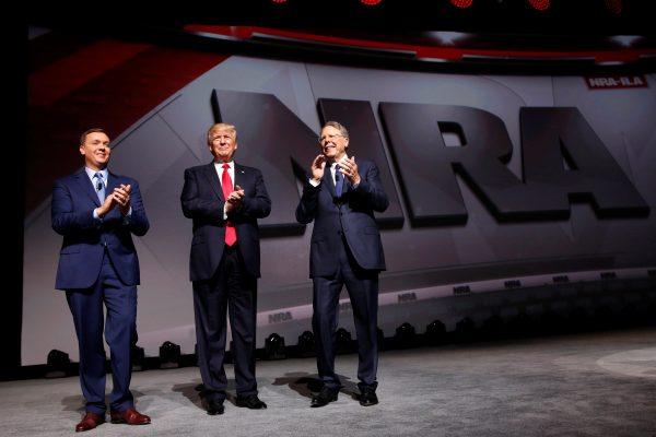 NRA Executive Director Chris Cox (L) and Executive Vice President and CEO Wayne LaPierre (R) welcome President Donald Trump (C) onstage to deliver remarks at the National Rifle Association (NRA) Leadership Forum at the Georgia World Congress Center in Atlanta, Ga., on April 28, 2017. (Jonathan Ernst via Reuters)