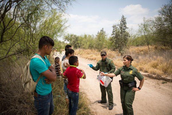 Border Patrol Agents talk to unaccompanied minors who just crossed over the U.S.–Mexico border, before loading them in a van for transport to an Office of Refugee and Resettlement facility, in Hidalgo County, Texas, on May 26, 2017. (Benjamin Chasteen/The Epoch Times)