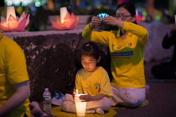 A mother and daughter join Falun Gong practitioners for a candlelight vigil in front of the Chinese Consulate in New York on July 16, 2017. Launched on July 20, 1999, the persecution is now entering its 18th year inside China. (Benjamin Chasteen/The Epoch Times)