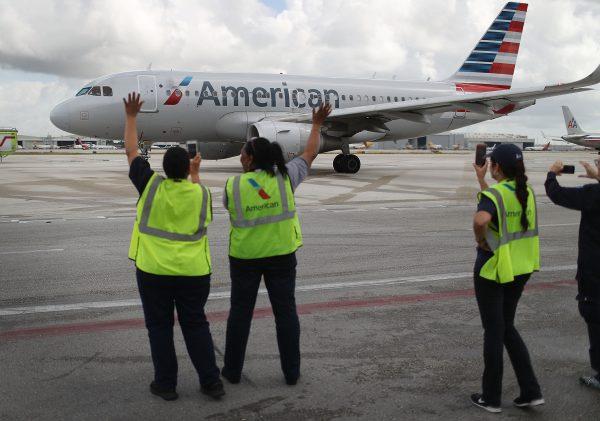 Employees waves to American Airlines flight on tarmac. (Joe Raedle/Getty Images)