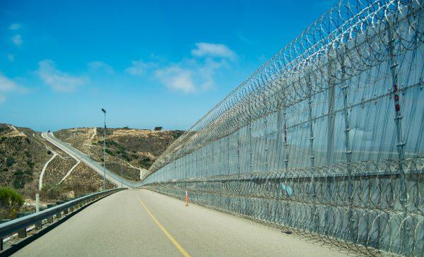 The secondary fence of the U.S.-Mexico border is near an area popularly known as "Smuggler's Gulch," in San Diego on July 12, 2017. The Border Patrol added a second layer of concertina wire along the bottom of the fence which helped curtail assaults on agents. (Joshua Philipp/The Epoch Times)