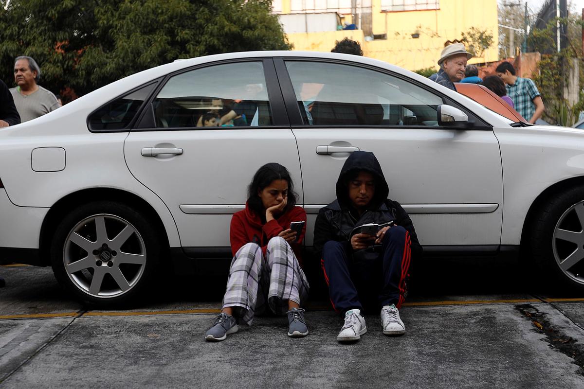 A couple sits beside a car inside a residential area after a tremor was felt in Mexico City, Mexico on Sept. 23, 2017. (REUTERS/Edgard Garrido)
