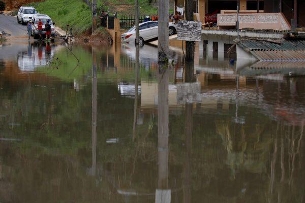 Local residents look at houses submerged by flood waters close to the dam of the Guajataca lake after the area was hit by Hurricane Maria in Guajataca, Puerto Rico September 23, 2017. (Reuters/Carlos Garcia Rawlins)