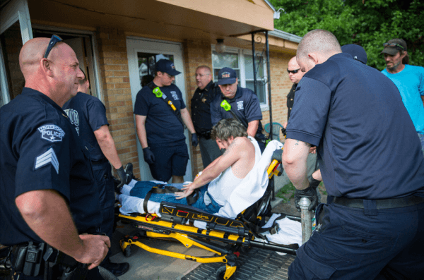  Local police, fire department, and deputy sheriffs help a man who is overdosing in Dayton, Ohio, on Aug. 3, 2017. (Benjamin Chasteen/The Epoch Times)