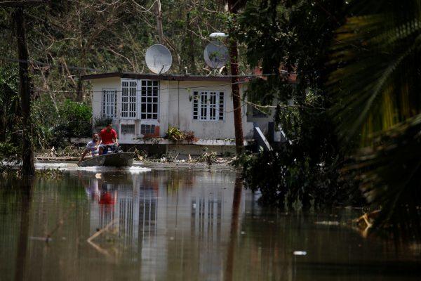 Local residents use a boat to pass next to a flooded house close to the dam of the Guajataca lake. (Reuters/Carlos Garcia Rawlins)