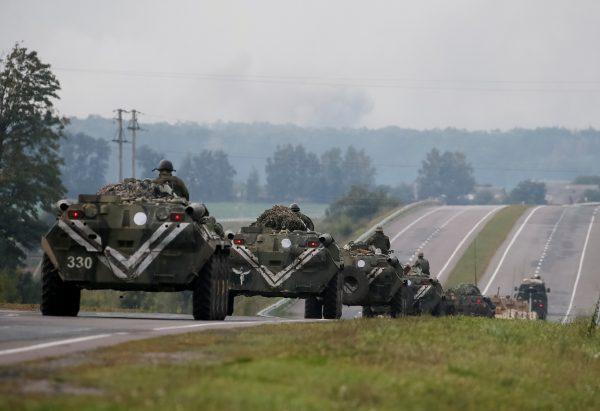 Armoured Personnel Carriers (APC) ride on the road as smoke rise over a warehouse storing ammunition for multiple rocket launcher systems at a military base in the town of Kalynivka in Vinnytsia region, Ukraine Sept. 27, 2017. (Reuters/Gleb Garanich)