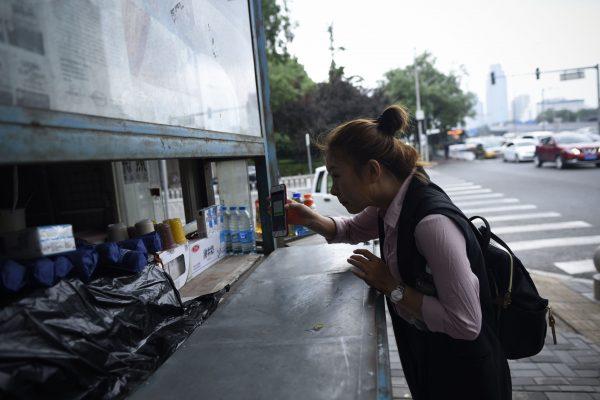 A woman showing payment to a vendor, sent via the Chinese instant messaging platform WeChat, at a street-side stall in Beijing. (Wang Zhao/AFP/Getty Images)