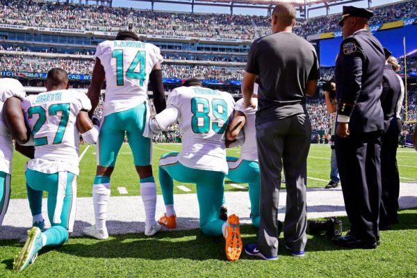Maurice Smith (#27) and Julius Thomas (#89) kneel, while Jarvis Landry (#14) of the Miami Dolphins stands during the National Anthem prior to an NFL game against the New York Jets at MetLife Stadium in East Rutherford, N.J., on Sept. 24, 2017. (Steven Ryan/Getty Images)