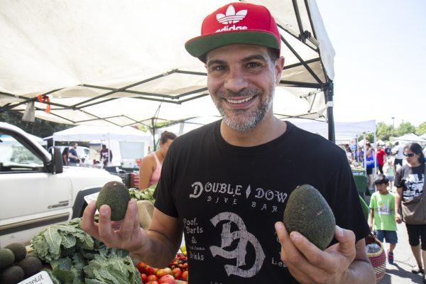 Chef Angelo Sosa holding avocados at the Vista Farmers Market. (Joshua Philipp/The Epoch Times)