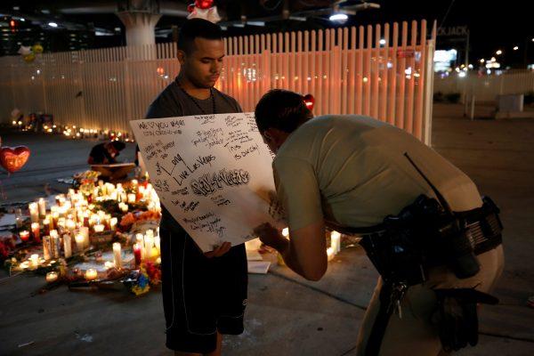 A police officer writes a message on a sign at a vigil on the Las Vegas strip following a mass shooting at the Route 91 Harvest Country Music Festival in Las Vegas, Nevada, U.S., October 2, 2017. REUTERS/Chris Wattie