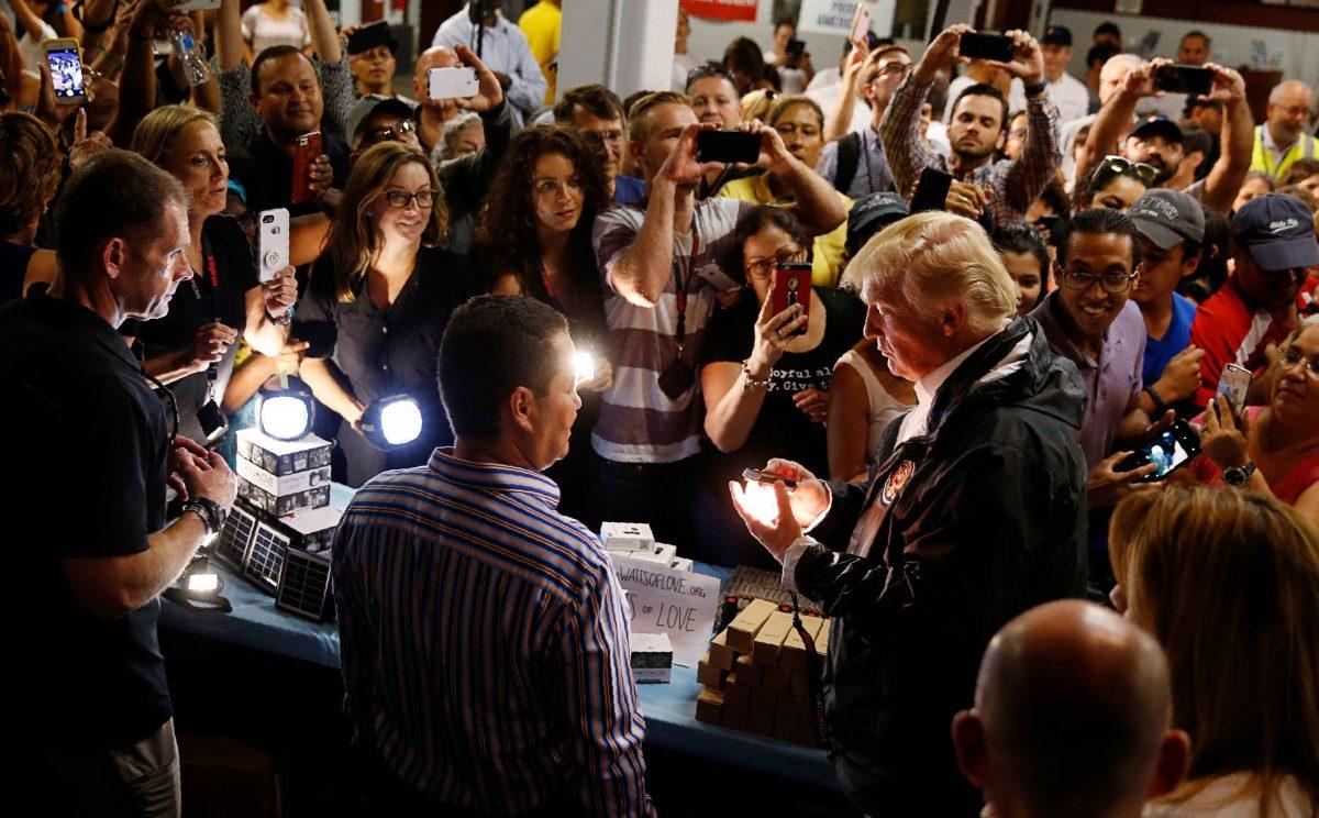 U.S. President Donald Trump examines emergency lights being given to a crowd of local residents affected by Hurricane Maria as he visits a disaster relief distribution point at Calgary Chapel in San Juan, Puerto Rico, U.S., Oct. 3, 2017. (REUTERS/Jonathan Ernst)