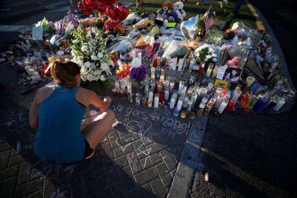 A woman draws with chalk at a makeshift memorial in the middle of Las Vegas Boulevard following the mass shooting in Las Vegas, Nevada, U.S., October 5, 2017. REUTERS/Chris Wattie