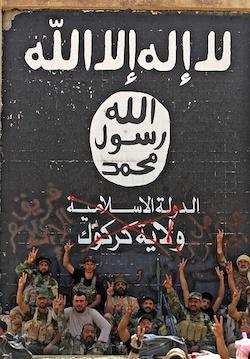 Fighters from the Hashed al-Shaabi (Popular Mobilization units), backing the Iraqi forces, pose in front of a mural depicting the emblem of the Islamic State (IS) group as troops advance through Hawija after retaking the city from ISIS militants on Oct. 5, 2017. (Ahmah Al-Rubaye/AFP/Getty Images)