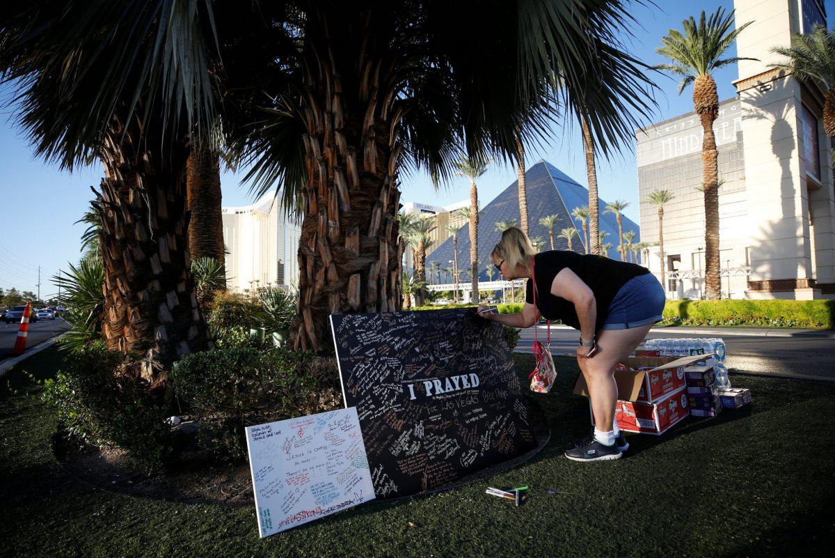 A woman writes a message on a sign at a makeshift memorial in the middle of Las Vegas Boulevard following the mass shooting in Las Vegas on Oct. 5, 2017. (Chris Wattie/Reuters)