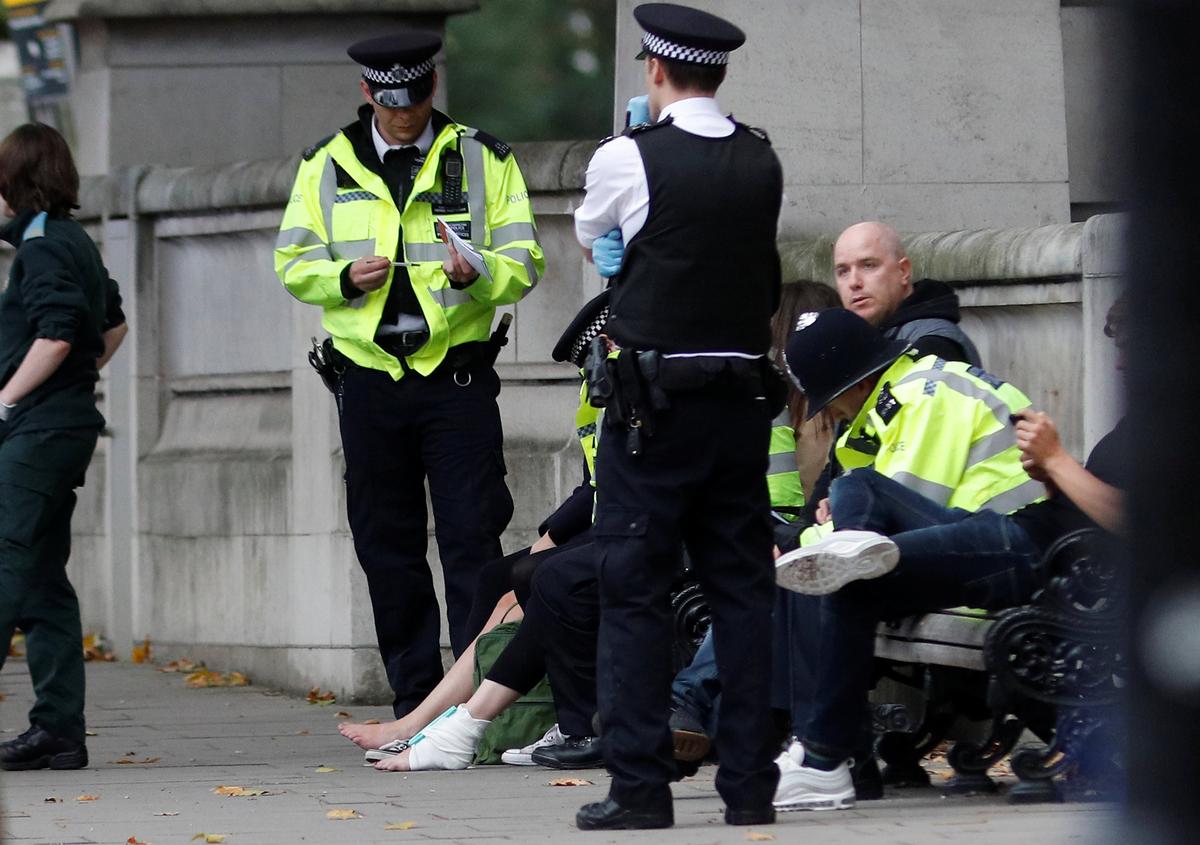 Police officers stand next to a person with a bandaged ankle near the Natural History Museum, after a car mounted the pavement, in London, Britain on Oct. 7, 2017. (REUTERS/Peter Nicholls)