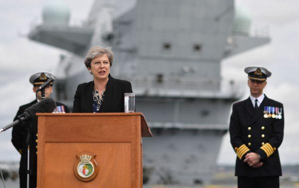 Prime Minister Theresa May stands on the flight deck and speaks to crew members of the HMS Queen Elizabeth after it arrived at Portsmouth Naval Base, its new home port in Portsmouth, England on Aug. 16, 2017. (Ben Stansall - WPA Pool/Getty Images)